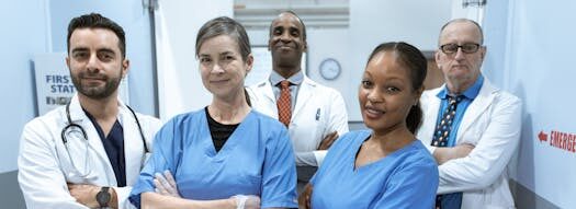A diverse team of doctors and nurses smiling confidently in a hospital setting.